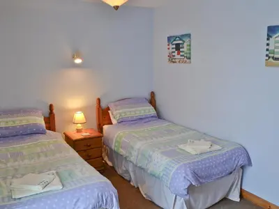 a bedroom with two beds and a night stand with a lamp at Brambles in St. Agnes