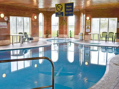 a swimming pool with tables and chairs in a building at Brambles in St. Agnes