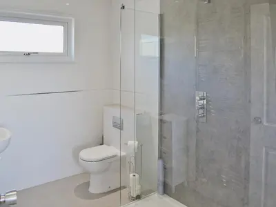 a bathroom with a toilet and a glass shower at Sand Dunes in Tywardreath