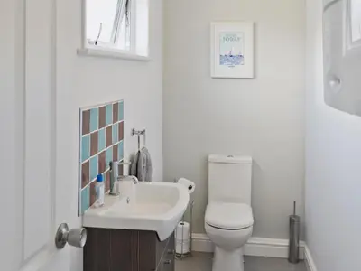 a white bathroom with a toilet and a sink at Sand Dunes in Tywardreath