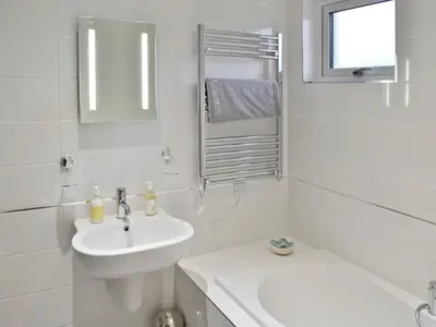 a white bathroom with a sink and a mirror at Sand Dunes in Tywardreath