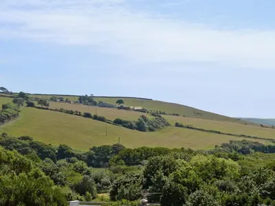 a green hillside with trees in the foreground at Sand Dunes in Tywardreath