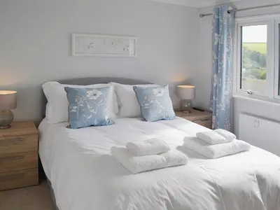 a white bed with towels on it with a window at Sand Dunes in Tywardreath