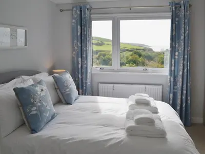 a bed with towels on it in front of a window at Sand Dunes in Tywardreath