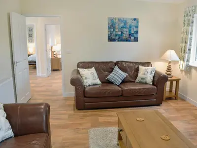 a living room with a brown leather couch and a table at Tegen in Tywardreath