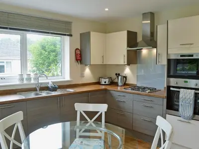 a kitchen with a sink and a counter with stools at Tegen in Tywardreath
