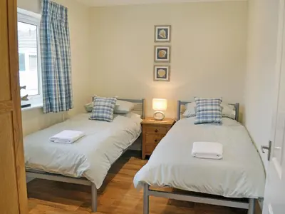two twin beds in a room with a window at Tegen in Tywardreath