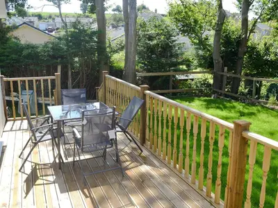 a patio with a table and chairs on a deck at Tegen in Tywardreath