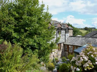 a stone house with a garden in front of it at Tucked Away in Linkinhorne