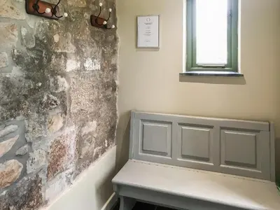 a bench in a room with a stone wall at The Roost in Saint Breward
