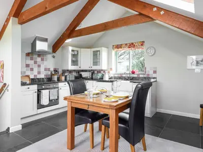 a kitchen with a wooden table and black chairs at The Roost in Saint Breward