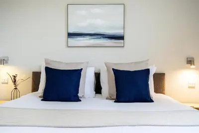 a bedroom with a bed with blue and white pillows at The Inn For All Seasons in Redruth