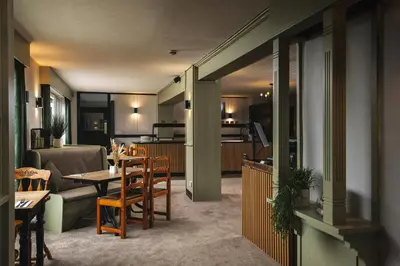 a living room with a table and a kitchen at The Inn For All Seasons in Redruth