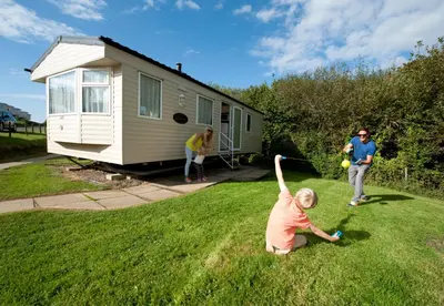 two people playing with a ball in front of a tiny house at Widemouth Bay Caravan Park in Bude