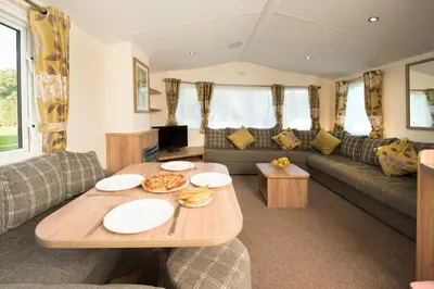 a living room with a table and a couch at Trelawne Manor Holiday Park in Looe