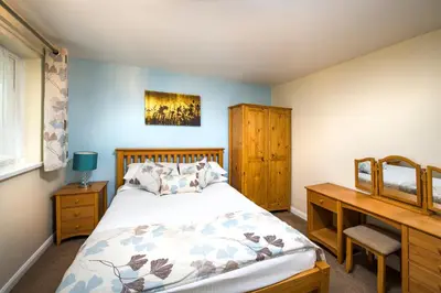 a bedroom with a bed and a wooden desk at Trelawne Manor Holiday Park in Looe