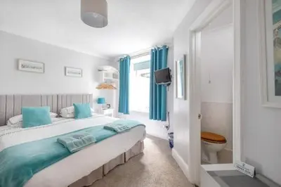 a white bedroom with a large bed and a window at Bridgeside Guest House in Looe