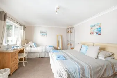 a bedroom with a large bed and a desk at Bridgeside Guest House in Looe