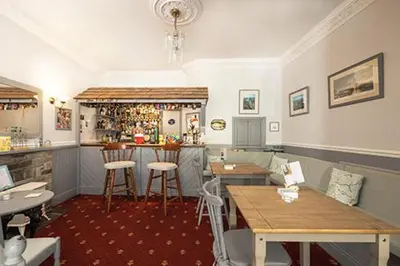 a restaurant with tables and a bar in a room at Bridgeside Guest House in Looe