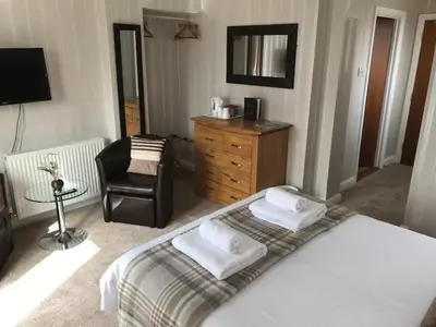 a bedroom with a bed and a chair and a mirror at Cotswold House in Falmouth