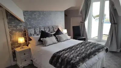 a bedroom with a large bed and a window at Cotswold House in Falmouth