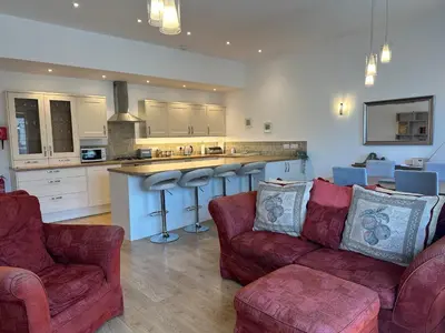 a living room with two couches and a kitchen at Tidemill House Apartment in Falmouth