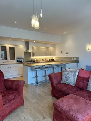 a living room with two red couches and a kitchen at Tidemill House Apartment in Falmouth