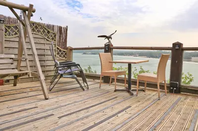 a deck with chairs and a table and a bird on a pole at Seaside Apartment in Newquay