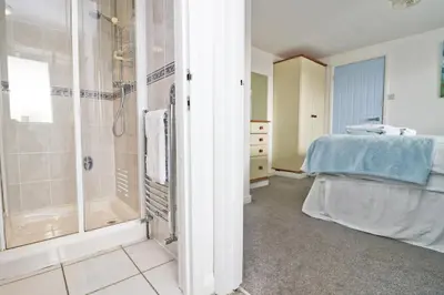 a bathroom with a shower and a bed in a room at Seaside Apartment in Newquay
