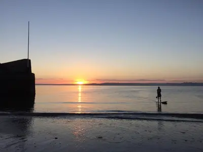 a person standing on the beach watching the sunset at East Crinnis Log Cabin in Par