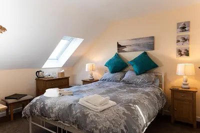 a bedroom with a large bed with blue pillows at Bosayne Guest House in Tintagel