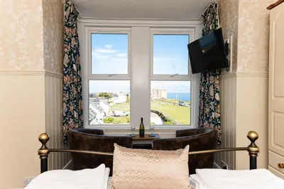 a bedroom with a bed and a window and a television at Bosayne Guest House in Tintagel
