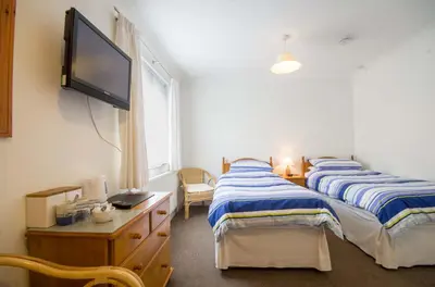two beds in a room with a tv on the wall at Seaview in Looe