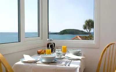 a dining room table with a view of the ocean at Seaview in Looe