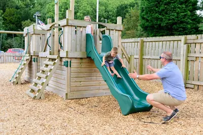 a man and a child playing on a playground at The Britannia Inn and Restaurant in Par