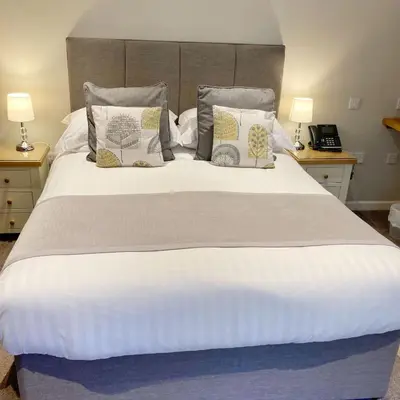 a large white bed with pillows on it at The Britannia Inn and Restaurant in Par