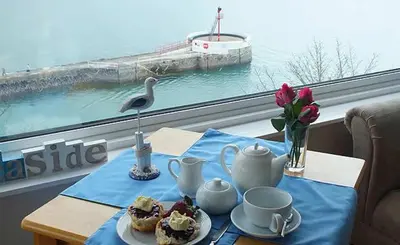 a table with a blue table cloth with tea sets on it at The Watermark in Looe