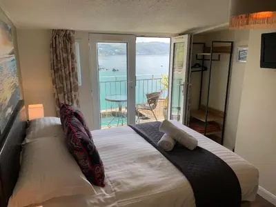 a bedroom with a bed with a view of the ocean at The Watermark in Looe