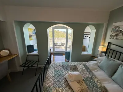 a bedroom with a bed and a desk and two windows at The Watermark in Looe