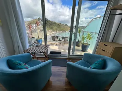a room with two blue chairs and a large window at The Watermark in Looe