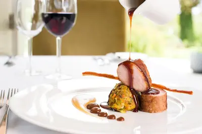 a plate of food on a table with a glass of wine at The Cornwall Hotel Spa & Lodges in St Austell