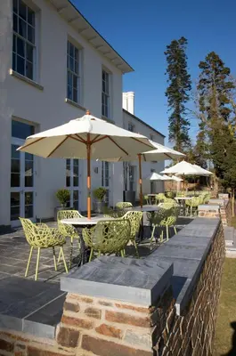 a patio with tables and chairs and umbrellas at The Cornwall Hotel Spa & Lodges in St Austell
