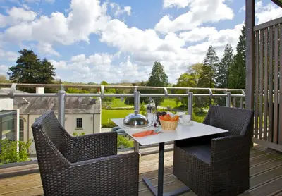 a patio with a table and chairs on a deck at The Cornwall Hotel Spa & Lodges in St Austell
