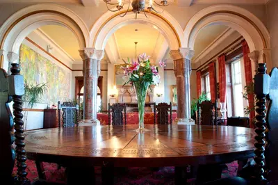 a dining room table with a vase of flowers on it at Camelot Castle Hotel in Tintagel