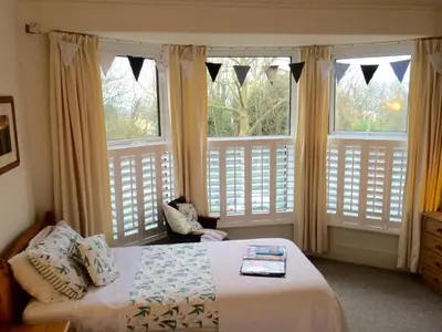 a bedroom with a bed and two large windows at Trelawney Guest House Room only in Falmouth