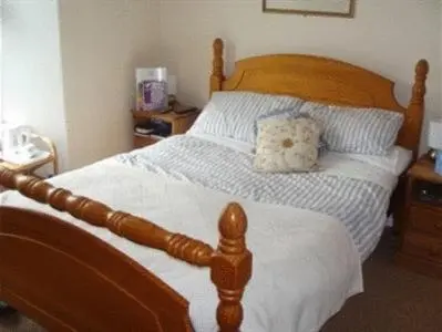 a bedroom with a wooden bed with a pillow on it at Trelawney Guest House Room only in Falmouth