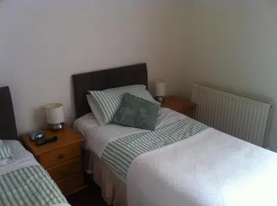 a bedroom with two twin beds and two night stands at Trelawney Guest House Room only in Falmouth