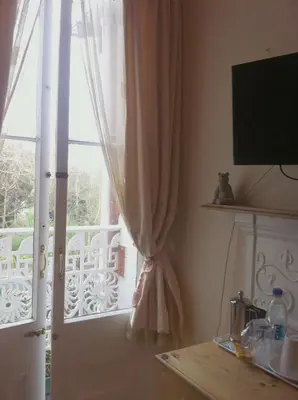 a window with a curtain and a door with a balcony at Trelawney Guest House Room only in Falmouth