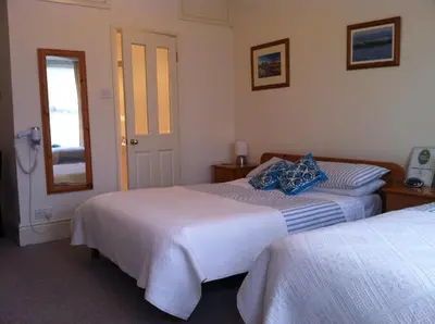a bedroom with two beds and a mirror at Trelawney Guest House Room only in Falmouth