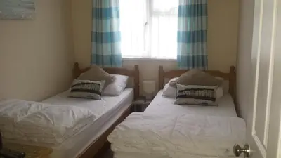 two beds in a small room with a window at Chalets & Lodges at Atlantic Bays Holiday Park in Padstow